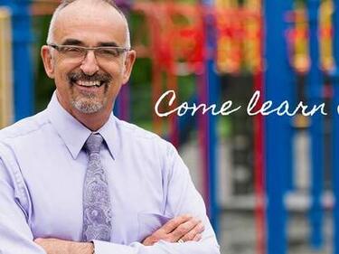 Principal standing in front of playground equipment