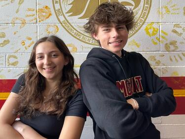 Two students, arms crossed and leaning into eachother