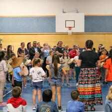 Student standing in a circle and drumming in front of other students and school community