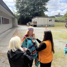 Three women, with one being blanketed for an Indigenous Honouring
